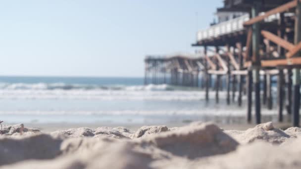 美国加利福尼亚，在木制水晶码头下面的沙堆上，海滩上的水波. — 图库视频影像