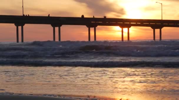 Muelle en agua de mar en la playa. Ondas oceánicas, cielo al atardecer. Sensaciones de costa de California. — Vídeos de Stock