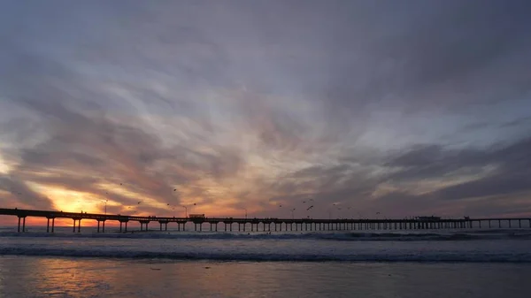 Molo w wodzie morskiej na plaży. Fale oceaniczne, niebo o zachodzie słońca. Wibracje wybrzeża Kalifornii. — Zdjęcie stockowe