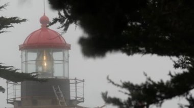Eski deniz feneri mercekleri parlıyor, sisli yağmurlu hava. Aydınlatılmış Beacon USA