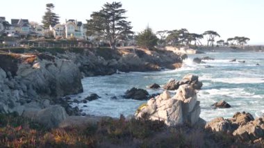 Kayalık okyanus sahilleri, dalgalar çarpıyor, Monterey, California sahil evleri.