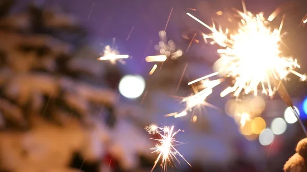Sparkler firework burning, Christmas tree in snow, New Year or Xmas bengal light