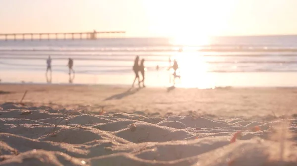 People walking on sandy Ocean Beach by pier at sunset, California coast, USA. — Stock Photo, Image