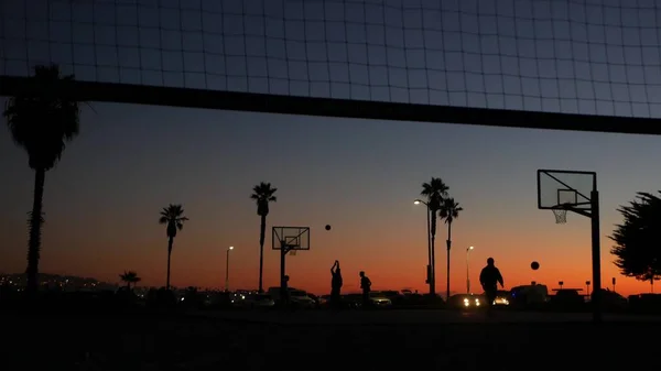 Jogadores em quadra de basquete jogando jogo de bola de cesta, praia do pôr do sol, Califórnia. — Fotografia de Stock