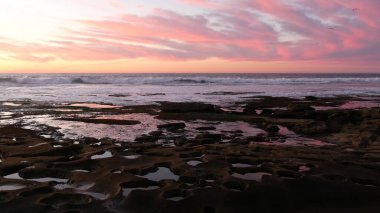 Kaliforniya 'da gelgit havuzu kaya oluşumu. Günbatımı gökyüzü yansıması suda.