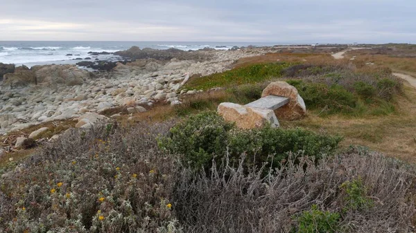 Rotsachtige grillige oceaan kust, zee golven, Monterey California. Houten lege bank. — Stockfoto