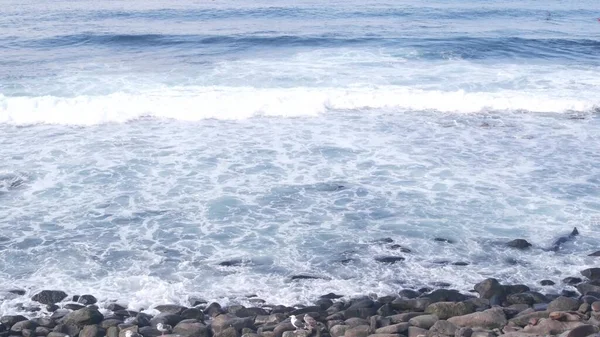 Vague de l'océan s'écrasant sur la plage, surface de l'eau de mer. Rochers ou pierres de galets sur la côte — Photo