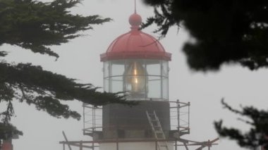Eski deniz feneri mercekleri parlıyor, sisli yağmurlu hava. Aydınlatılmış Beacon USA