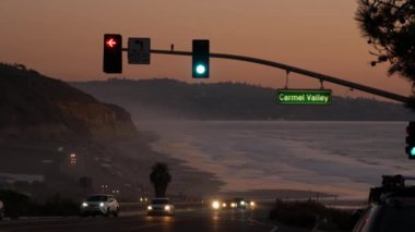 Trafik ışıkları, Pasifik kıyısı otoyolu, California. Alacakaranlıkta okyanus boyunca yolculuk