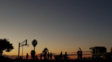 Basketbol sahasında basketbol oynayan oyuncular, günbatımı plajı, California.