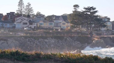 Kayalık okyanus sahilleri, dalgalar çarpıyor, Monterey, California sahil evleri.