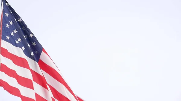 American flag waving in wind, USA. National symbol waves in breeze on flagpole.