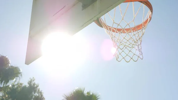 Orange hoop, net and backboard for basket ball game. Basketball court outdoors.