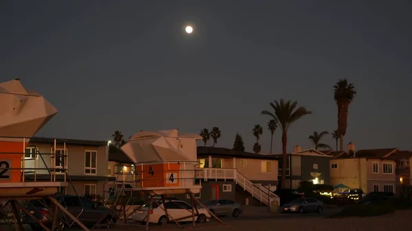Palmy a měsíc na soumračné obloze, Kalifornské pobřeží plavčík, plážové domy. — Stock fotografie