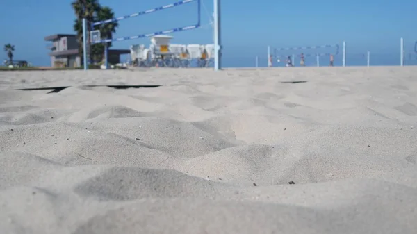 Players playing volleyball on beach court, volley ball game with ball and net.