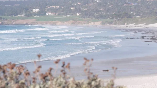 Ocean sandy beach, California coast, sea water wave crashing. Sunny weather, fog