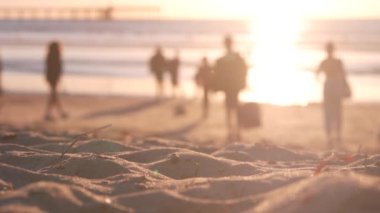 Kumlu Okyanus Sahili 'nde yürüyen insanlar gün batımında rıhtımda, Kaliforniya kıyılarında, ABD.