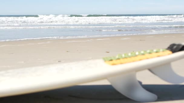 Surfboard para surf deitado na areia da praia, costa da Califórnia, EUA. Ondas oceânicas. — Vídeo de Stock