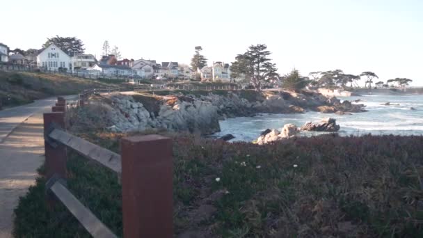 Rocky ocean beach, waves crashing, Monterey, California coast beachfront houses. — Stock Video