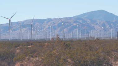 Dönen yel değirmenleri türbini, rüzgar çiftliği veya elektrik santrali alternatif yeşil yenilenebilir enerji jeneratörleri, Kaliforniya 'daki sanayi bölgesi, Mojave Çölü, Tehachapi, ABD. Rüzgâr çiftliğinde elektrik üretimi.