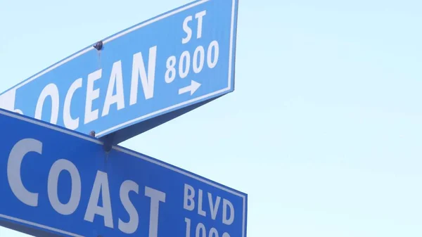 Coast and Ocean street road sign on crossroad, California city, USA. Waterfront tourist resort near Los Angeles, beachfront travel destination for waterside summer vacations. Coastal vacations vibes.
