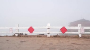 Çıkmaz sokağa park etmek yok. Yol sisli okyanus sahillerinde bitiyor, Kaliforniya kıyısı, ABD. Şehir caddesinde bulutlu hava ve trafik işaretleri var. Tahta çitin üzerindeki kırmızı taş blöfle.