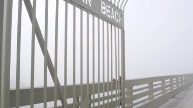 Ocean Beach rıhtımındaki sisli Kaliforniya sahilindeki metal kapı, ABD. San Diego sahilinde sisli, karamsar, bulutlu bir hava. Sakin bir atmosfer. Kasvetli depresif sis içinde rıhtım girişi.