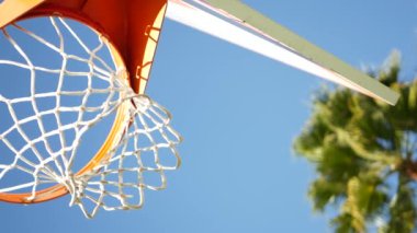 Basketbol sahası, turuncu halka, dışarıda basket maçı için ağ ve sedye. Sokak sahasında ya da oyun sahasında eğlence amaçlı spor aletleri. Mavi gökyüzü ve sahil palmiyeleri, Kaliforniya ABD.