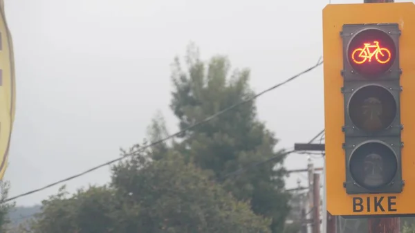 Yellow traffic light or stoplight signal for bicyclists on crossroad, California USA. Bike lane on streets crossing or intersection. Transport infrastructure for safety biking or cycling in city.