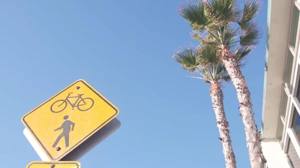 歩行者と自転車交差警告黄色の道路標識市内通り カリフォルニア州 ヤシの木と空 注意または注意標識を固定し 自転車とペッド 自転車や自転車の交通安全 — ストック写真