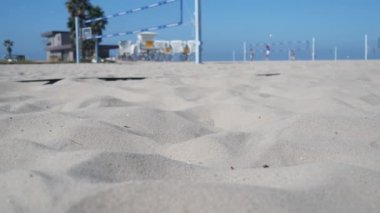 Plaj kortunda voleybol oynayan oyuncular, top ve ağla voleybol oyunu, Kaliforniya sahili, ABD. Spor sahasında odakları kesilmiş insanlar, kumlu okyanus kıyısında. Kusursuz döngüsüz sinemagraf arkaplanı.
