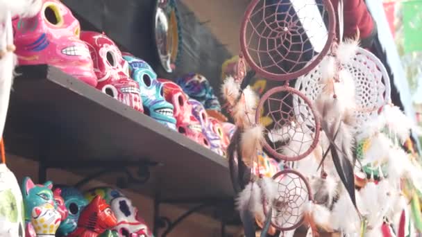 市場の屋台でメキシコのお土産 カラフルな塗装頭蓋骨や夢のキャッチャー 多色鮮やかな民族の装飾品 バザーや市場 カウンターで販売するためのセラミック細工の死のシンボル 死者の日 — ストック動画