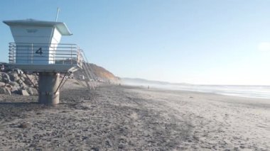 Dik uçurum, kaya ya da kayalık, California sahili erozyonu, Del Mar, San Diego, ABD. İnsanlar aşınmış kayalıklarda yürüyor. Torrey Pines eyalet plajı, okyanus dalgaları. Cankurtaran kulesi, cankurtaran istasyonu ya da kulübe.