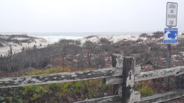 Ocean beach písečné duny, Monterey, Kalifornie mlhavé pobřeží, USA. Mlhavý deštivý podzim, zimní počasí, šedá oblačnost. Stezka po břehu, studené mořské vlny. Varovné znamení, nebezpečí tsunami. Pozor na nebezpečí.