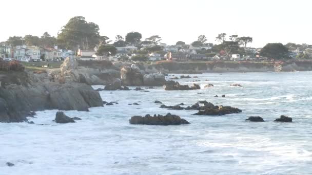 ロッキー険しい海のビーチ 海岸でクラッシュする海の波 モントレー17マイルドライブ カリフォルニア州海岸 パシフィックグローブ 海岸沿いのウォーターフロントの遊歩道 水辺の歴史的家屋 植民地時代の建築 — ストック動画