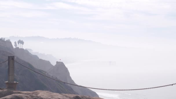 陡峭而不稳定的悬崖 岩石或悬崖 多雾的天气 加利福尼亚海岸侵蚀 派恩维斯塔 侵蚀的峭壁忽略了观点 海浪从上方涌来 安全远行的链条护栏 — 图库视频影像