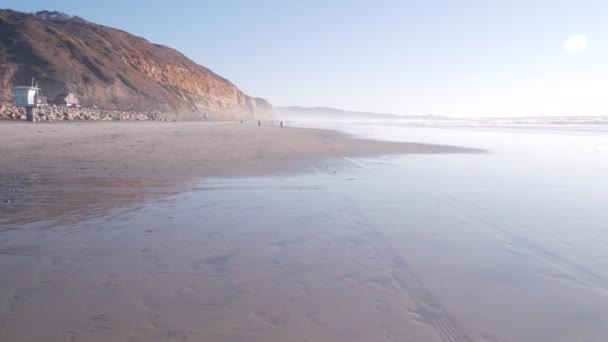 カリフォルニア州の海岸浸食 デルマー サンディエゴ 米国の急な崖 岩または崖 人々は干拓地の砂の上を歩く トーリーパインズ州の海のビーチ 低潮位の水の波 霧の多い天気 — ストック動画