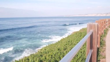 Okyanus dalgaları sahile çarpıyor, yukarıdan deniz suyu yüzeyi, uçurum ya da kayalık, La Jolla kıyısı gezinti güvertesi, California USA. Pasifik kıyılarındaki sulu yeşil buz bitkisi. Deniz manzarası ve korkuluklar.