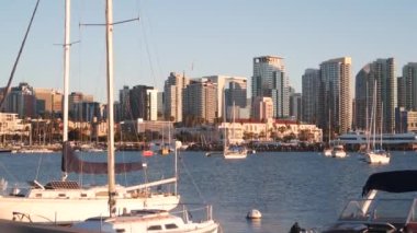 Yat marinada ve şehir merkezinde günbatımında ufuk çizgisi, San Diego şehir manzarası, California sahili, ABD. Yükselen gökdelenler, körfezde bir tekne, rıhtım güvertesi. Limanda kentsel mimari ve yelkenli.