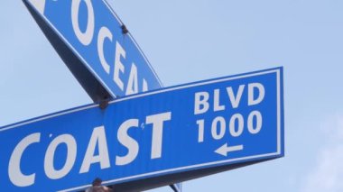 Coast ve Ocean Caddesi kavşağındaki trafik levhası, Kaliforniya, ABD. Los Angeles yakınlarındaki rıhtım turizm merkezi, deniz kıyısındaki yaz tatilleri için gidilecek yer. Kıyı tatilleri titreşimleri.