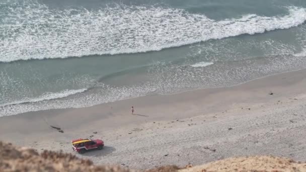 ライフガードレッドピックアップトラック 砂の上のライフガード自動車 カリフォルニア海のビーチUsa 救助は上からのサーフの安全 ライフセーバー車および海の波の流れのための海岸で車を拾う トーリー松の崖 — ストック動画