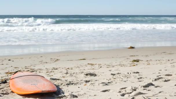 美国加利福尼亚海岸海滩沙滩上冲浪的冲浪板 海浪和橙色冲浪板或桨板 水上水上运动用的长板或水槽 岸上的体育活动 — 图库视频影像