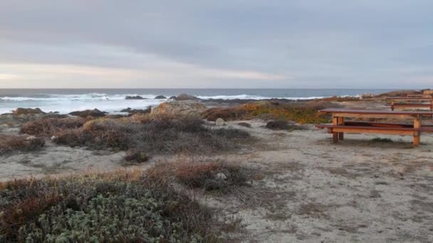落基陡峭的太平洋海岸 海浪冲击着岩石 17英里的车程 加利福尼亚州蒙特雷 靠近Lobos角 Big Sur 卵石海滩的多姿多彩的大自然 木制的空长椅在小径上休息 — 图库视频影像