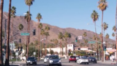 Odaklanamayan palmiye ağaçları, güneşli Palm Springs şehir trafiği, Los Angeles, California, ABD yakınlarındaki tatil beldesi. Dağlık vadide iklim çölleri vahası, yaz gezisi atmosferi. Araba sürüyor..