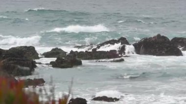 Rocky pasifik okyanus kıyıları, kayalara çarpan deniz dalgaları, 17 mil sürüş, Monterey, California USA. Point Lobos, Big Sur, Pebble plajı yakınlarındaki kasvetli doğa. Dramatik bulutlu, yağmurlu, soğuk hava.
