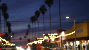 Ocean Beach 'teki sönük palmiye ağaçları, Kaliforniya' nın alacakaranlık ışıkları, San Diego, ABD. Akşam vakti, palmiye ağaçları ve arabalar geliyor. Liman kenti caddesinde parıldayan aydınlık çelenkler.