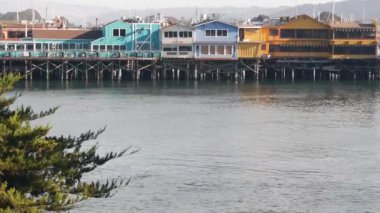 Yığınlar, sütunlar ve sütunlar üzerindeki renkli ahşap evler, okyanus suyu, tarihi Eski Balıkçılar İskelesi, Monterey Körfezi veya limanı, Kaliforniya kıyısı ABD. Turist sahili gezinti alanı, sahil şeridi..