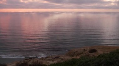 Gün batımında dramatik bulutlar, pembe gökyüzünün yansıması, bulutlar. Torrey Pines 'ın manzaralı manzaralı manzaralı manzaralı, yukarıdan okyanus suyu dalgaları. Dik uçurum, kaya ya da kayalık, Kaliforniya kıyıları, ABD.