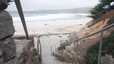 Carmel 'deki Ocean Sandy Beach, Monterey Bay Doğa, California Sahili, ABD. Büyük köpüklü deniz dalgaları kıyıya çarpıyor. Deniz kıyısındaki tatil beldesi. Sisli hava, merdivenler, merdivenler.