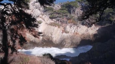 Kaya, kayalık ya da uçurum, koya düşen okyanus dalgaları, su sıçrayan deniz. Big Sur, 17 mil yol, Point Lobos eyalet parkı deniz manzarası, Monterey, Kaliforniya kıyısı ABD. Kozalaklı çam selvisi ormanı ya da koruluğu